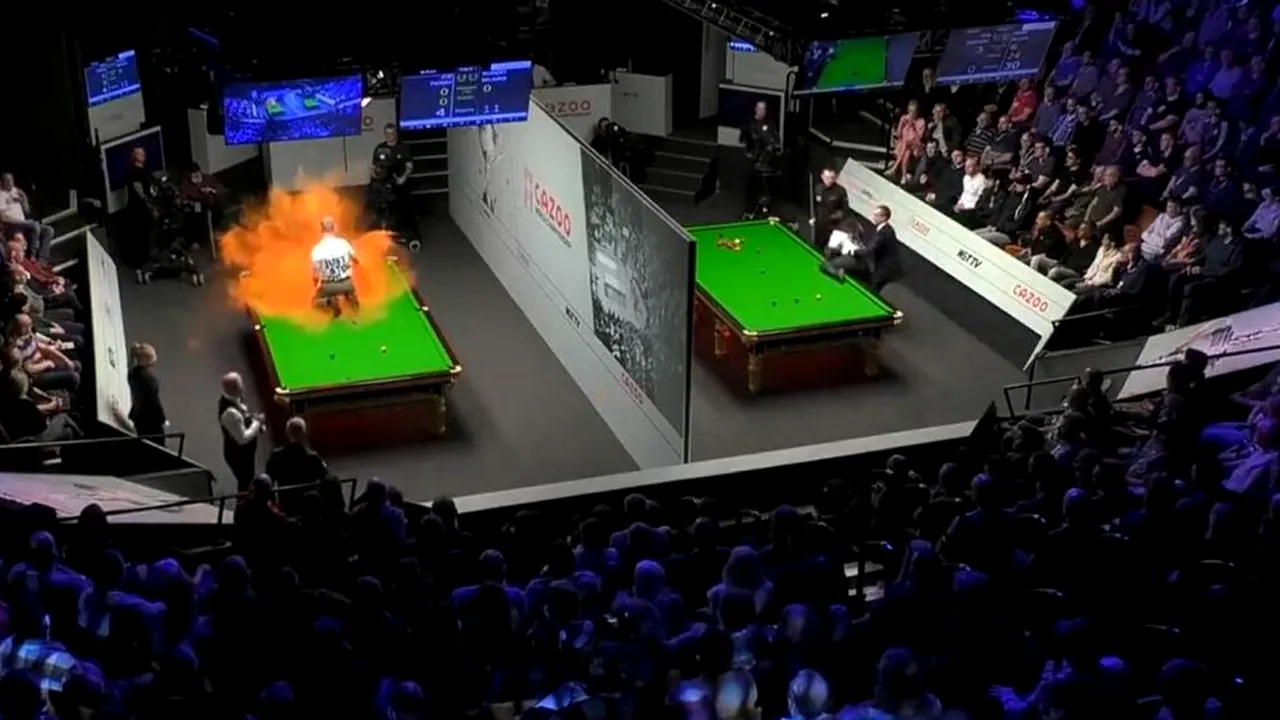 Scene halucinante la Campionatul Mondial de snooker! Așa ceva nu s-a mai întâmplat! Un protestatar s-a urcat pe masă în timpul meciului și a distrus-o după ce a împrăștiat un praf portocaliu! La masa alăturată s-a încercat același gest extrem! VIDEO